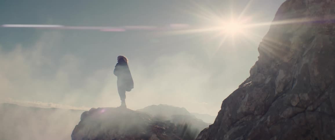 A woman covers her face with a scarf as dust blows on her in the desert