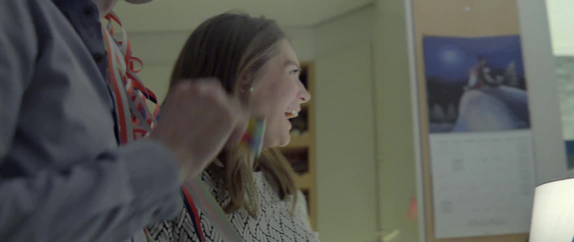 A smiling woman and her friends celebrate with colorful party favors and festive streamers.
