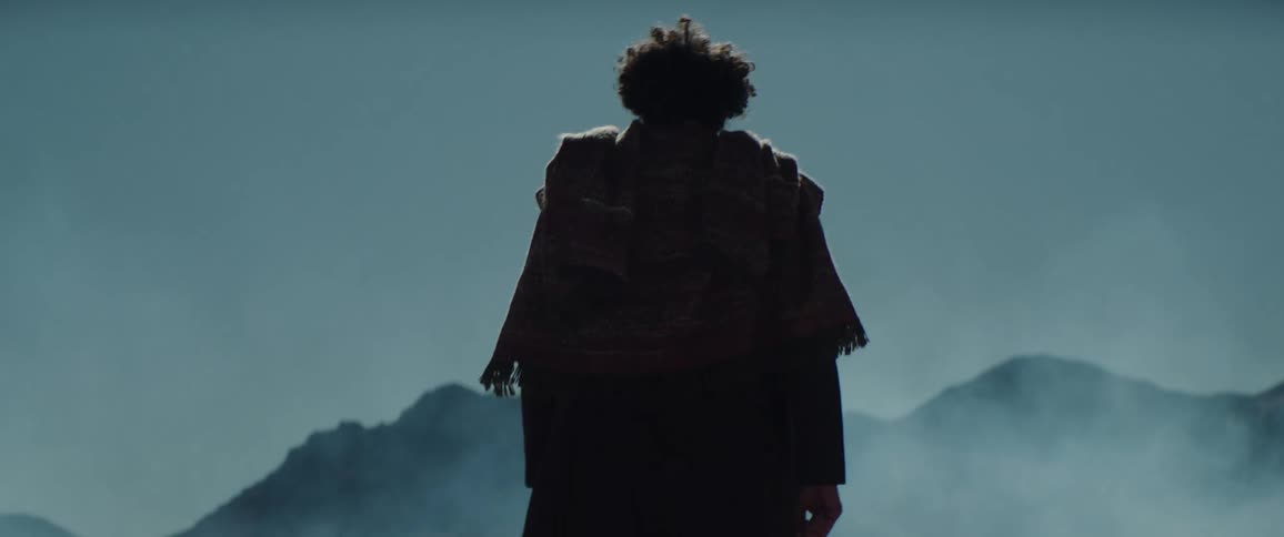 A man slowly walks across a barren flatland during the day