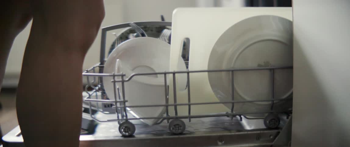 A woman is taking things out of a dishwasher during the day