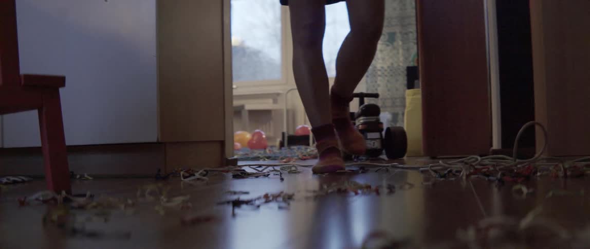A person walks across a dusty and dirty wooden floor inside a home.