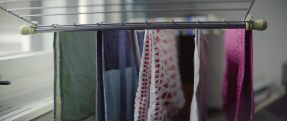Domestic scene of laundry being hung to dry on a foldable indoor rack.