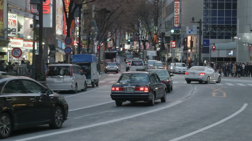 Cars and pedestrians travel on a city street