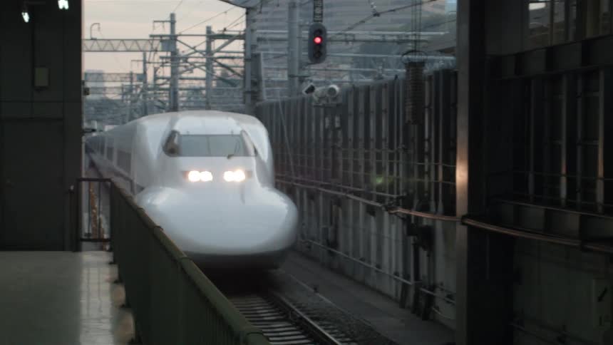 A thin white train drives by