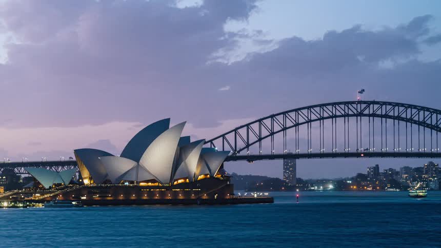 Boats and ferries traveling under the sydney harbor bridge near the opera house