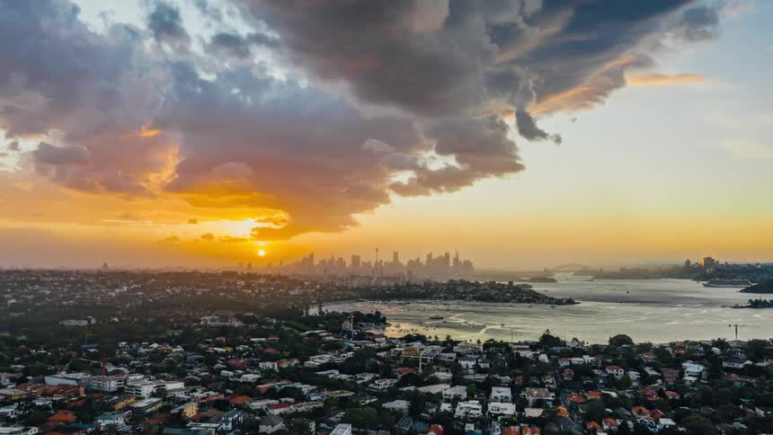 Clouds floating over a large city and bay at sunset