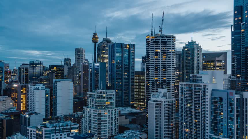 Lights on tall buildings and skyscrapers light up a big city at night and fade as the daylight comes and a new day begins