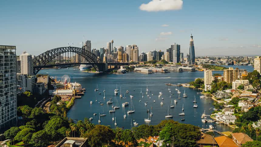 Boats anchored and traveling around the sydney harbor with bridge and city skyline