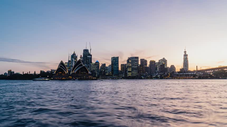 A time lapse of boats sailing in the water with a city skyline in the distance