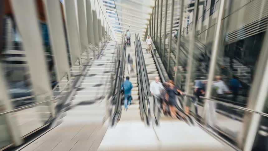Pedestrians walking on a city sidewalk and escalator