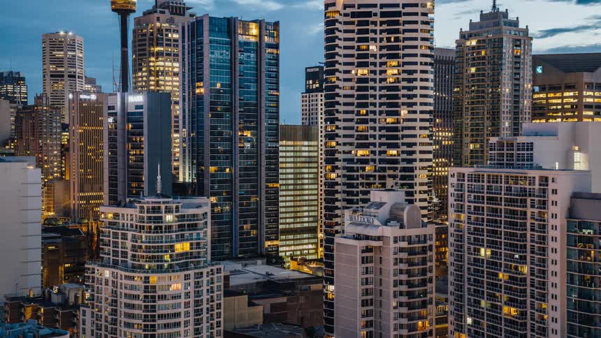 Lights on tall buildings and skyscrapers light up a big city at night and fade as the daylight comes and a new day begins