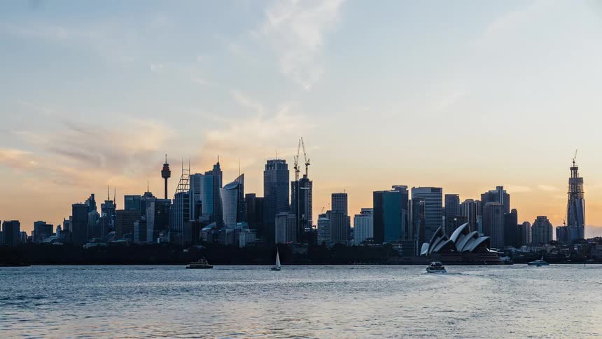 People are driving boats on the water near a downtown city