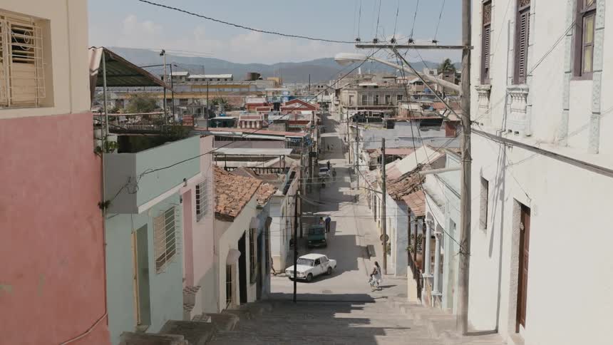 A staircase leading down to a narrow street in a city in Cuba during the day