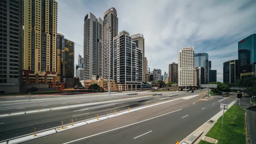 Cars and buses travel on a city highway with skyscrapers and buildings