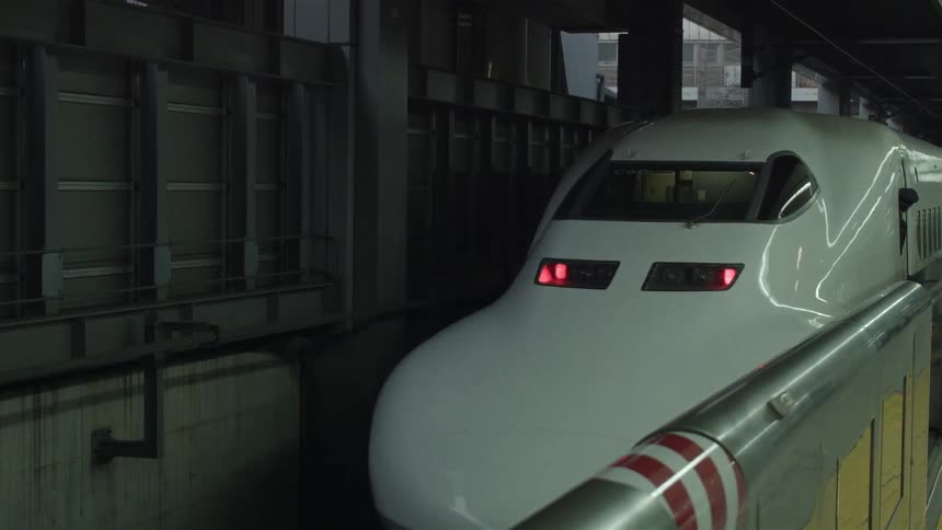 A commuter train slowly pulls away from a loading platform