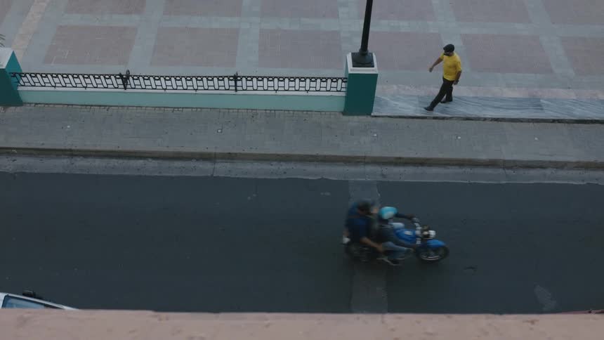 A man walking across a plaza and sidewalk gets ready to cross a street