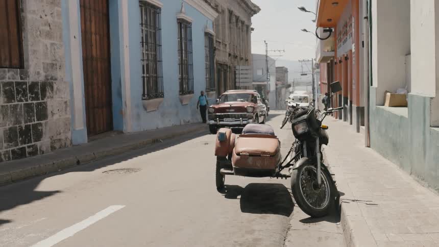A vehicle travels along a road through a city during the day