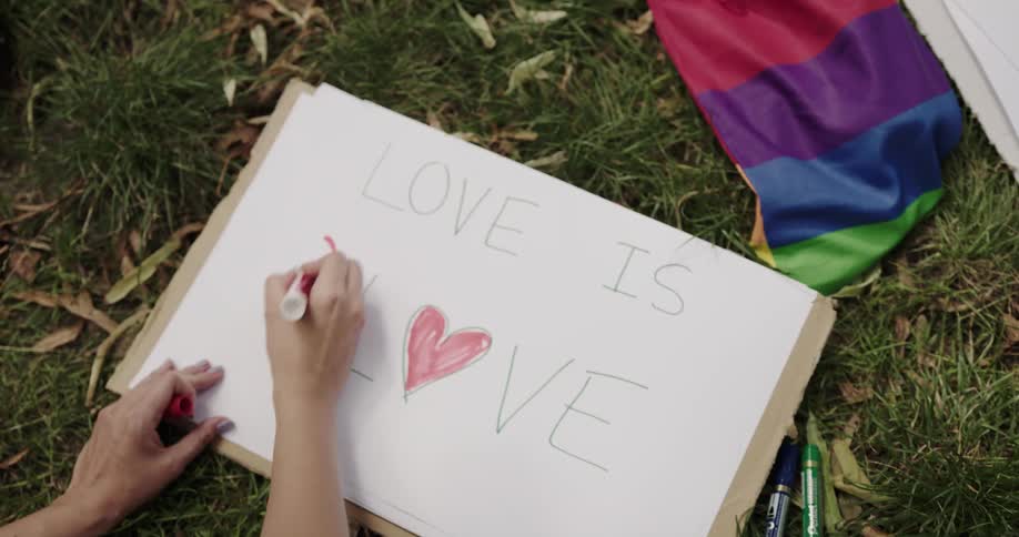 A young woman is lying on the grass and writing on a sign