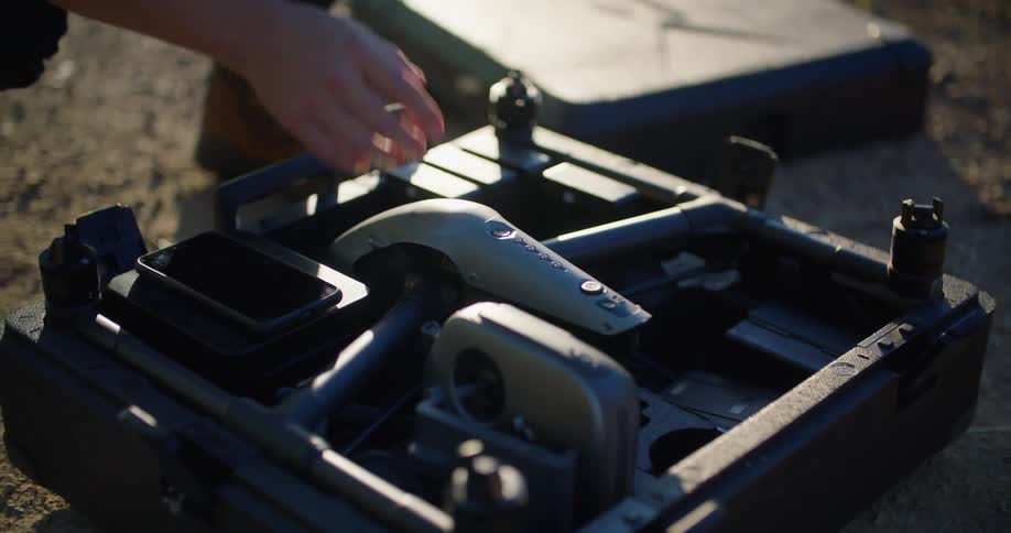 A person is outdoors and opening a box with a drone in it