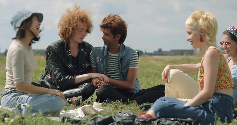 A group of friends are hanging in the grass in the outdoors