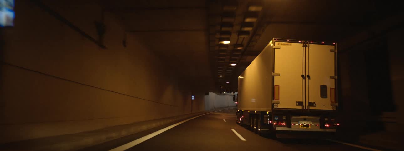 A semi truck is driving through a tunnel at dusk