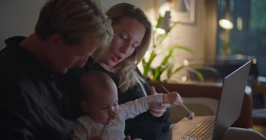 Parents hold their baby near the laptop