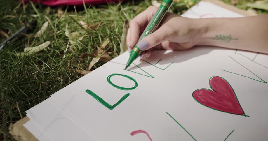 A person is writing on a poster in the grass