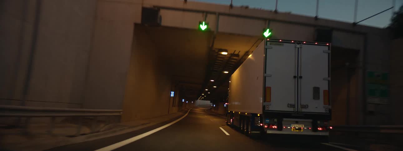 A semi truck travels on a highway and through a tunnel