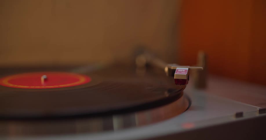 A turntable arm swings over and the needle drops down on a record album