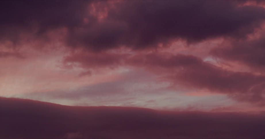 Dark pink clouds move across the sky