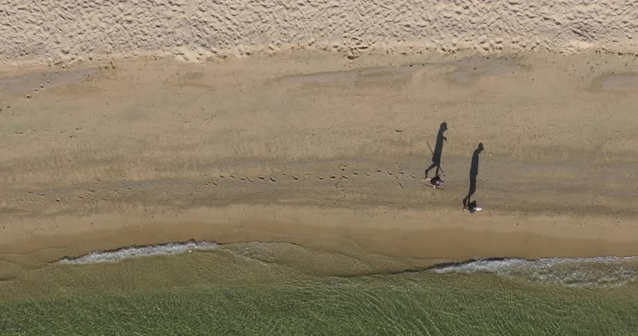 Two people are walking on the coast of the beach