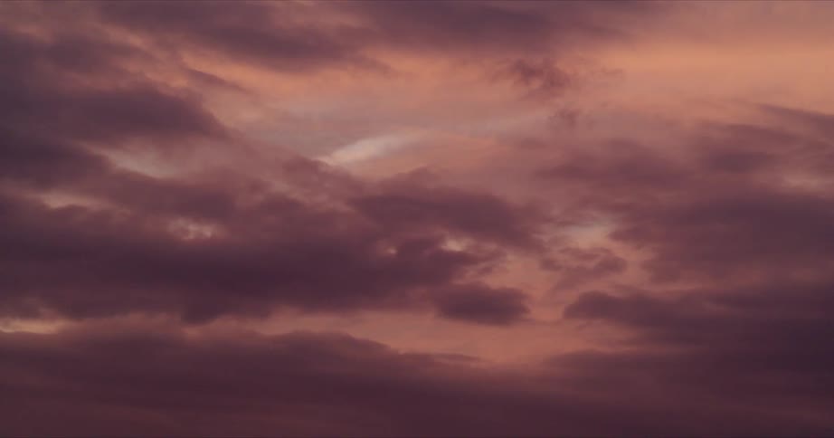 Dark pink clouds move across a colorful sky