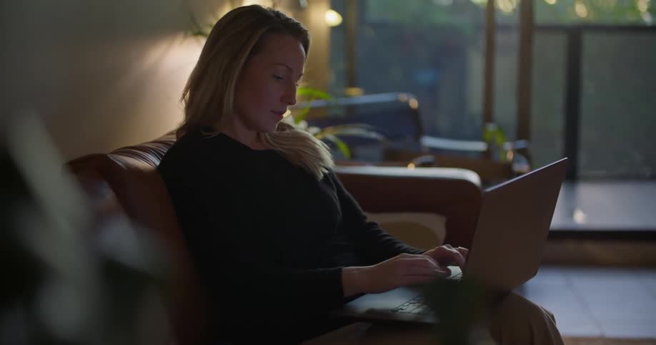 A woman is typing on a laptop and sitting indoors
