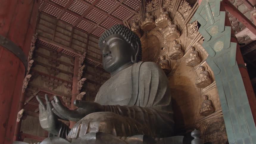 A statue of buddha sitting in a red, wood temple