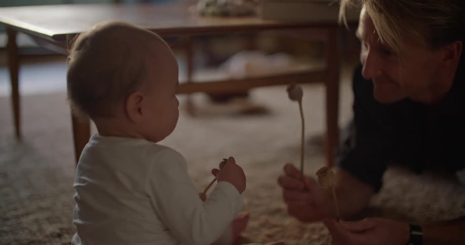 A man lies on the carpet at home and plays with his infant daughter