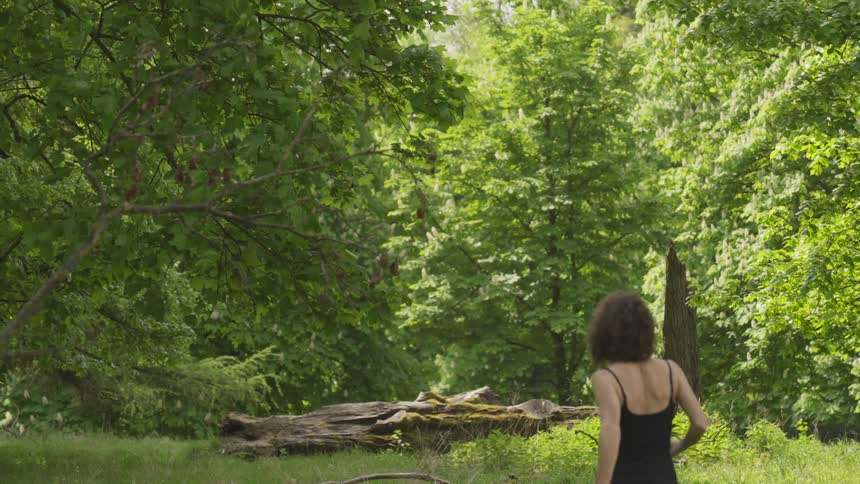 A woman is jogging outdoors in a forest during spring