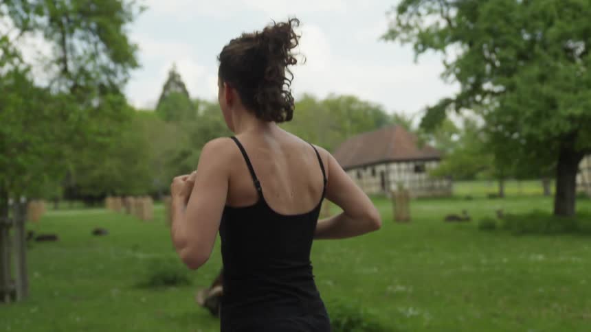 A woman is jogging outdoors in a rural area
