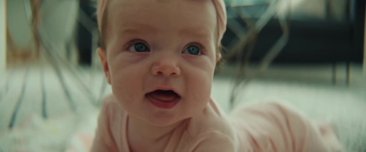 A baby girl smiling and laughing while lying on a living room rug
