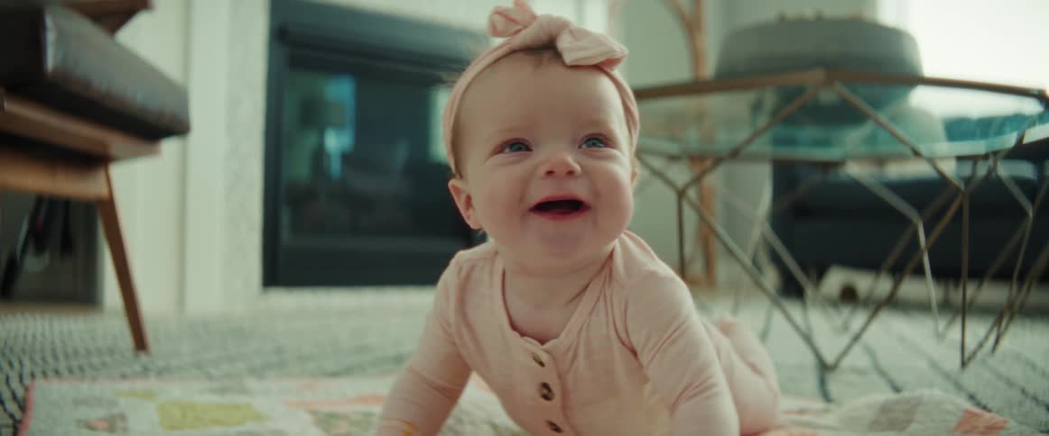 A baby is rolling on the ground in the living room