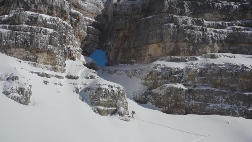 A skier hiking up a snowy mountainside in winter