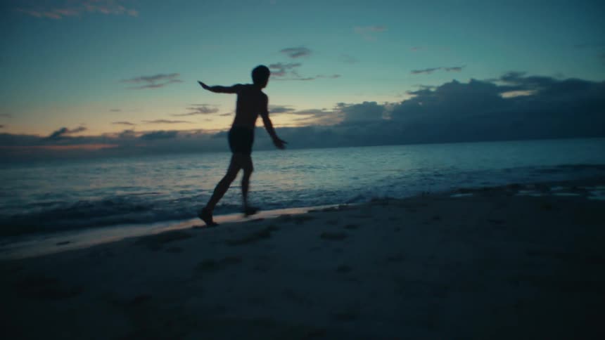 A person is running on the beach during sunset
