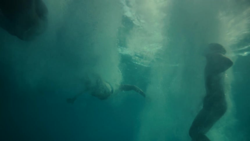 A man jumps into the ocean then swims back up to the surface treading water