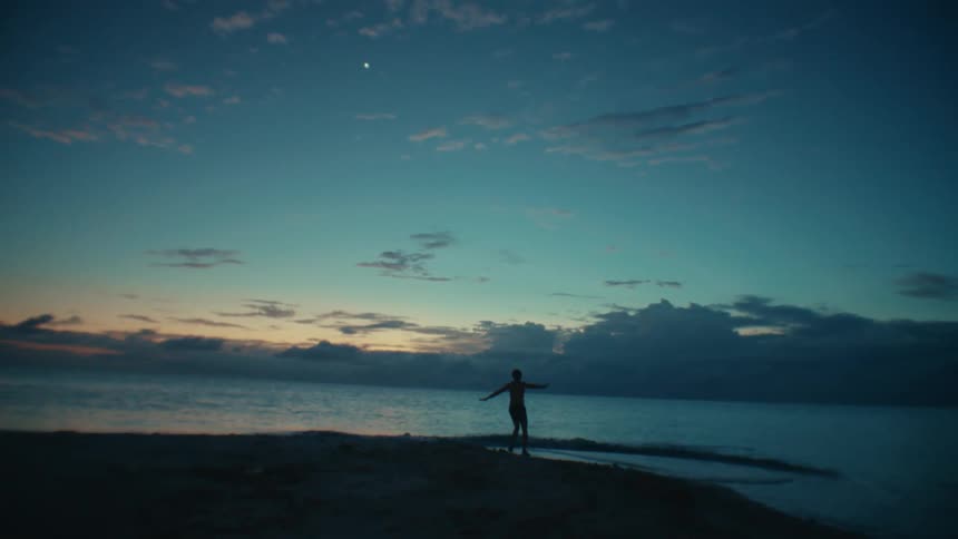 Silhouette of a man dancing on the beach and splashing in the water