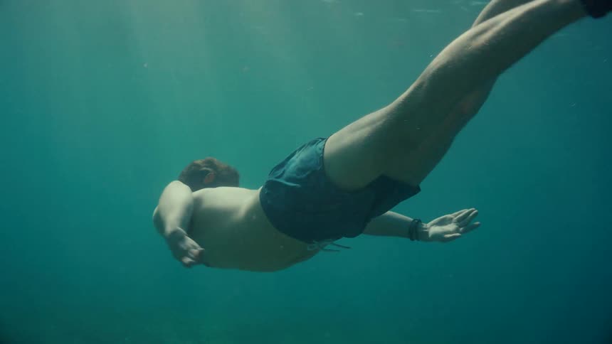 A teenage boy is swimming underwater and wearing diving fins