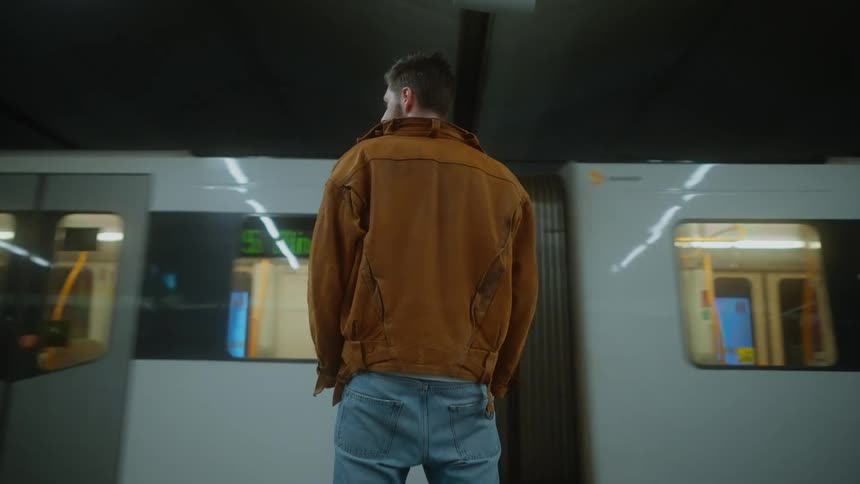 A man standing on a train platform as a subway train goes by