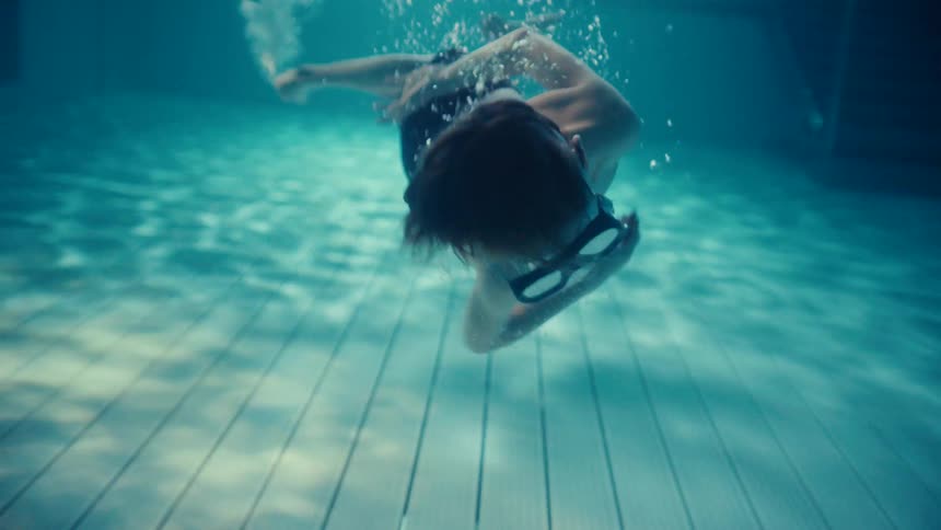 Youth rolls underwater near bottom of the swimming pool