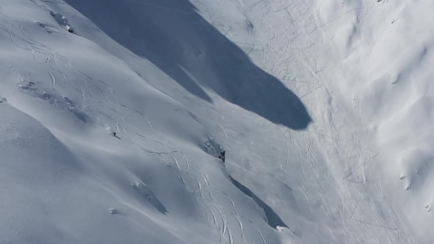 A skier coasts down the side of a snow covered mountain