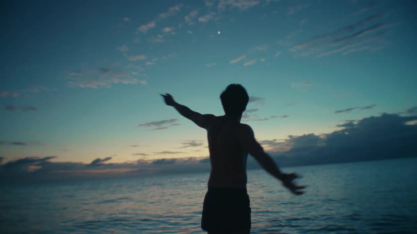 A man plays in the shallow ocean water during dusk