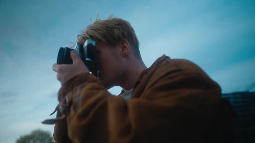 A young man is taking a picture outside in the city