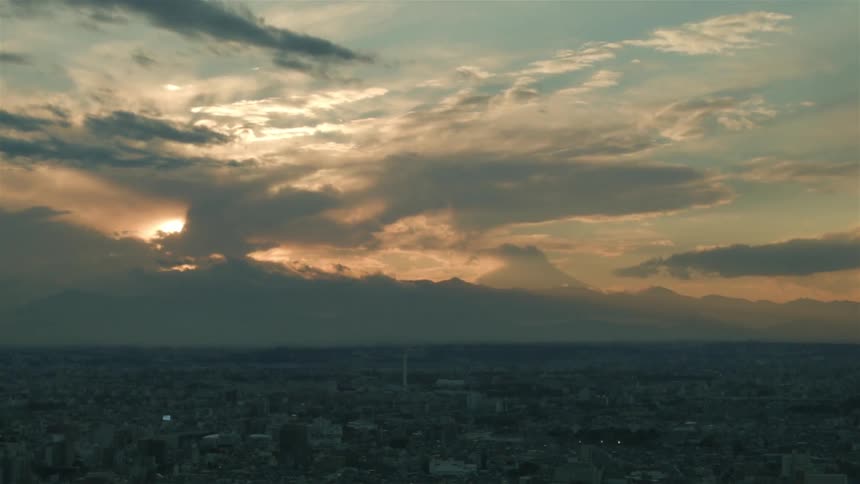 The sun sets over a city on a cloudy day